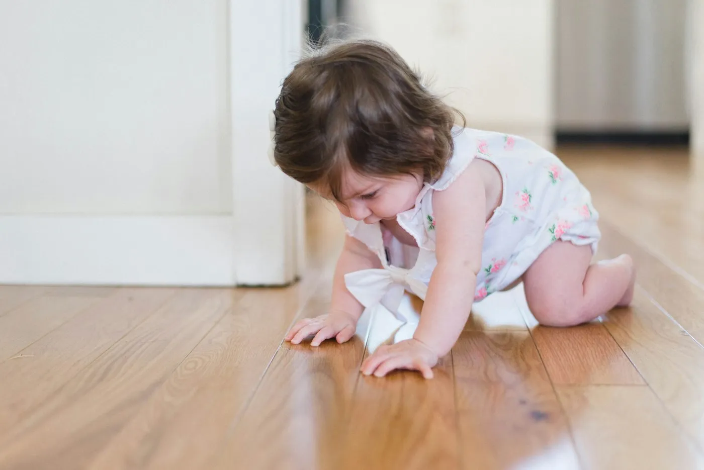 A baby crawling across a wooden floor
