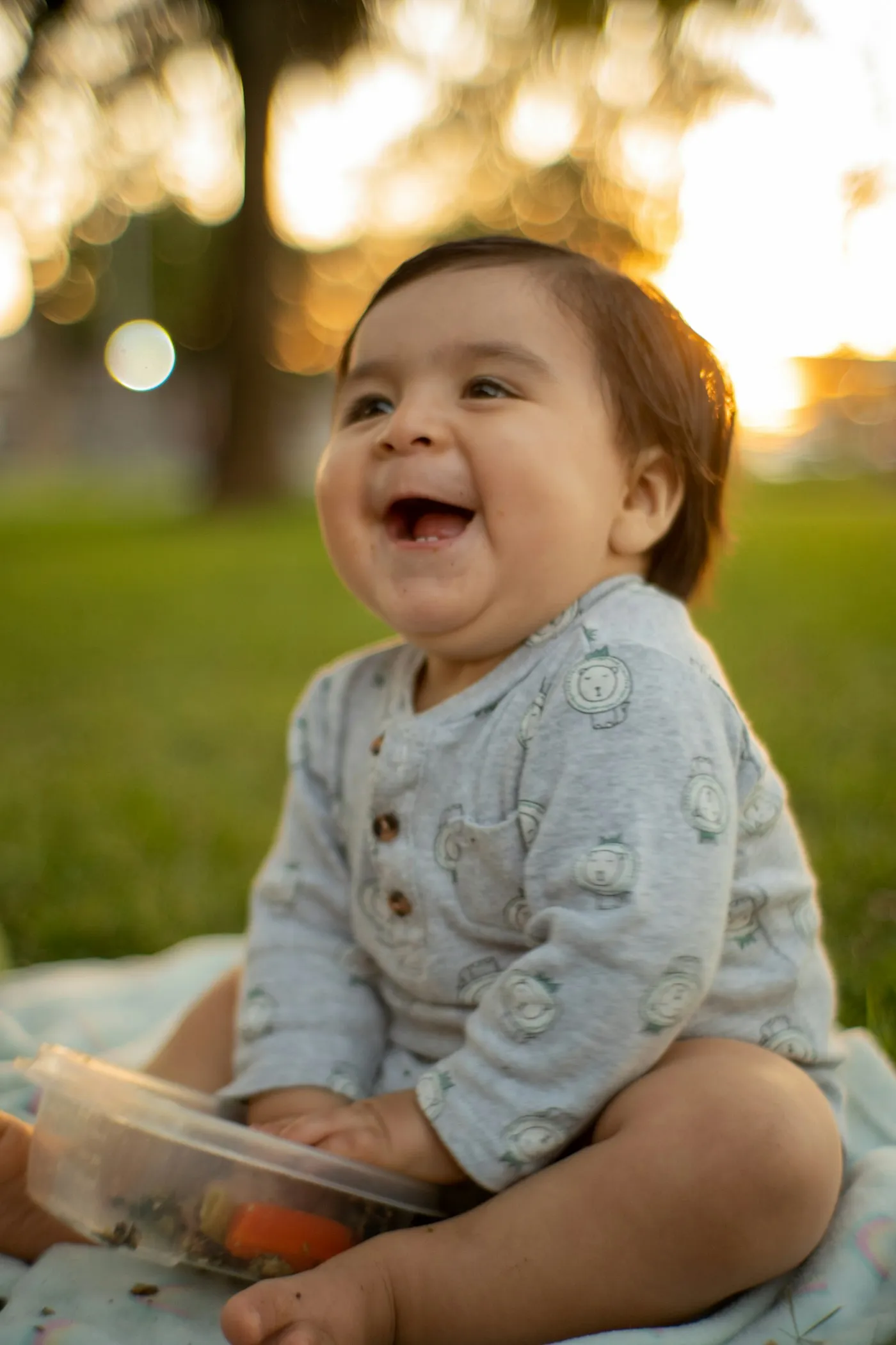 A baby laughing outdoors at sunset
