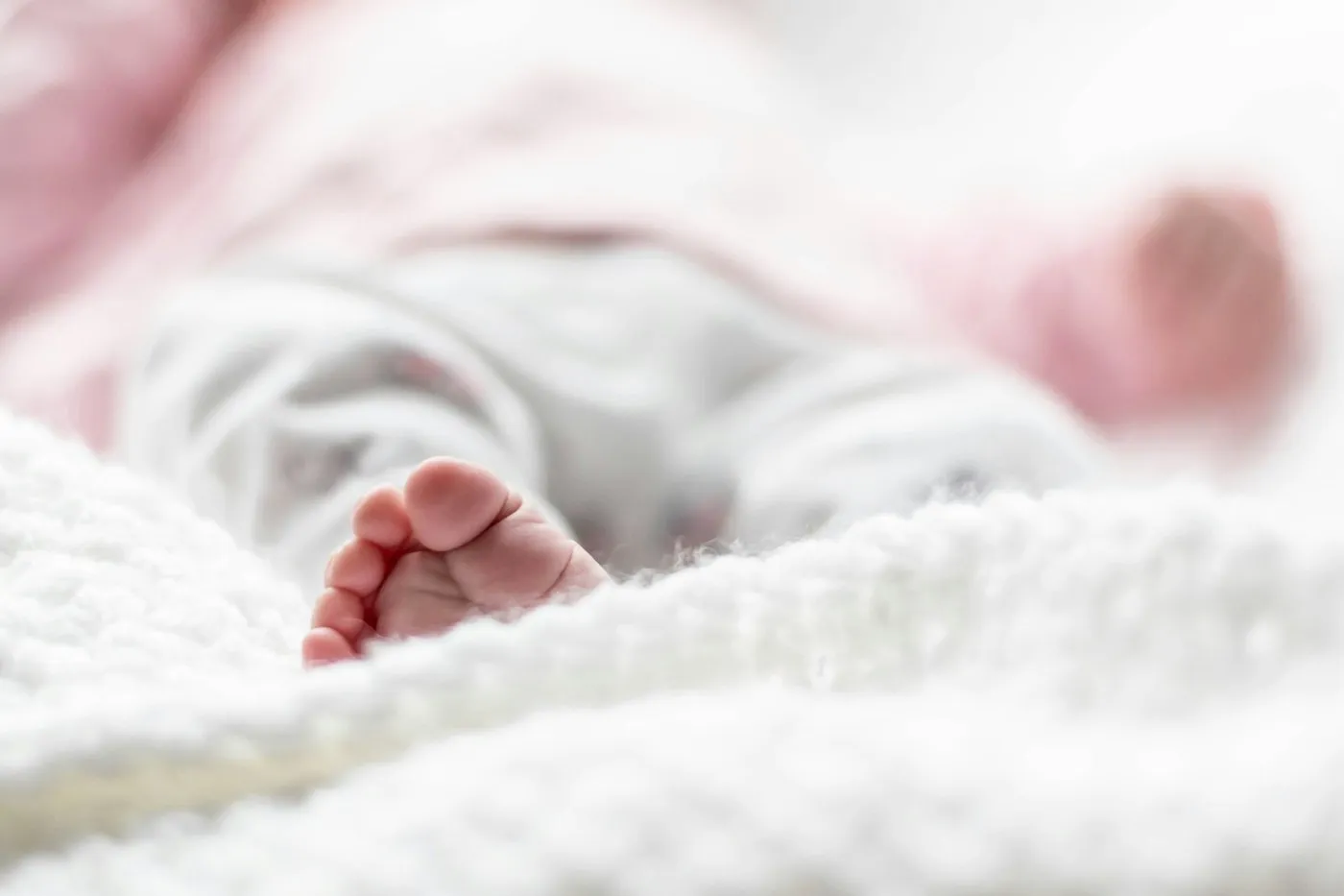 A newborn’s tiny feet on a white blanket